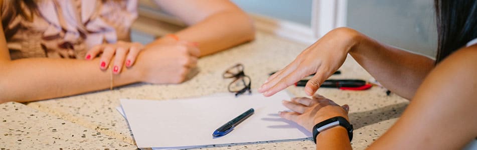 two people's hands next to a piece of paper